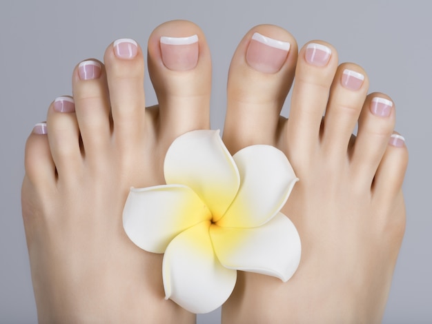 Free photo closeup photo of a female feet with white french pedicure on nails