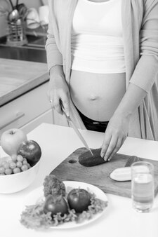 Крупным планом фото беременной женщины, делающей овощной салат на кухне