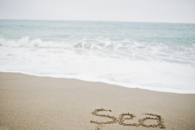 泡立つ波による砂の碑文の海のクローズアップ写真
