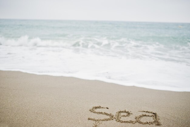 Closeup photo of sand inscription sea by the foamy waves