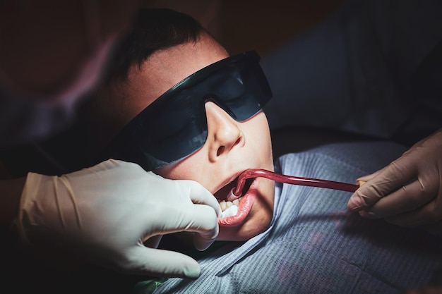 Closeup photo shoot of little child which gets dental operation by dentist and her assistant.