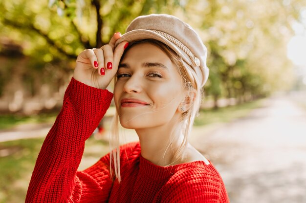 自然なメイクと魅力的な笑顔を持つ見事な金髪の女性のクローズアップ写真。素敵なスタイリッシュなセーターの素敵な女の子