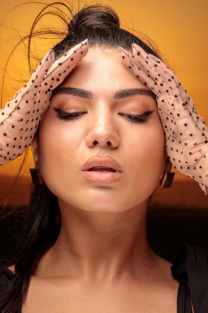 A closeup photo of a young lady closed her eyes and put her hands to her face High quality photo