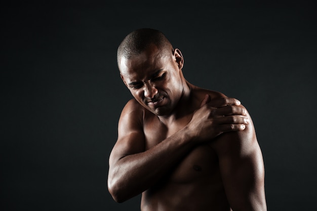 어깨 통증을 가진 젊은 벗은 아프리카 계 미국인 남자의 근접 촬영 사진