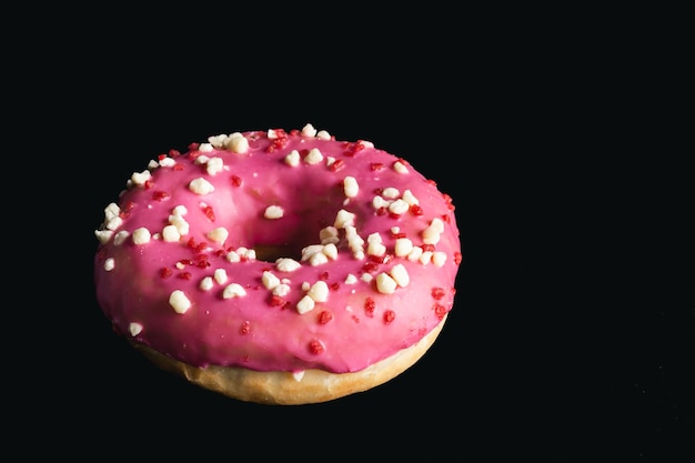 Free photo closeup pink donut on a black background