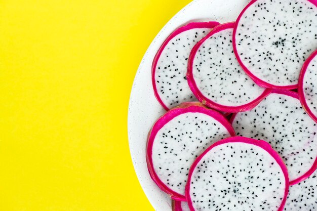 Closeup of a plate of dragon fruit slices on yellow background