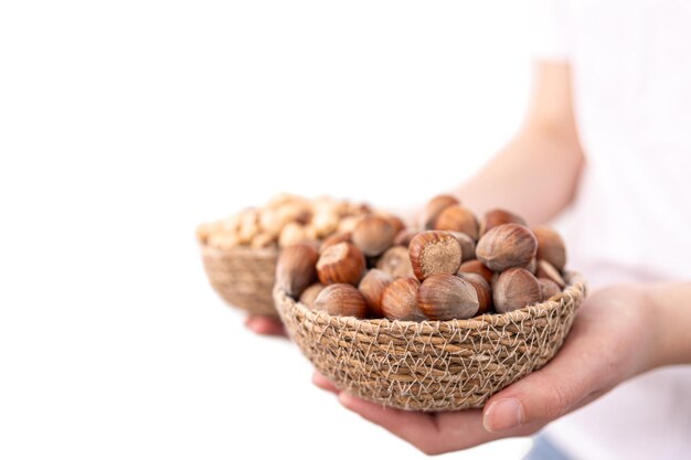Closeup of a plate of hazelnuts and macadamia nuts in female hands