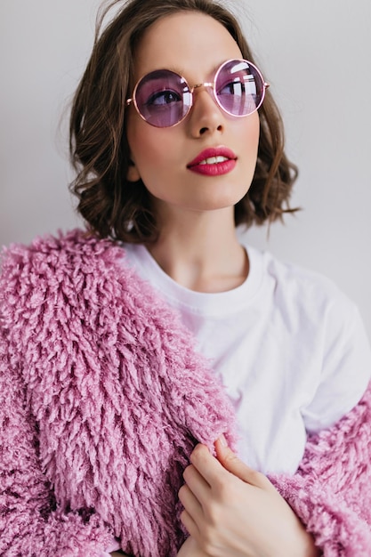 Foto gratuita ritratto del primo piano della ragazza castana attraente che distoglie lo sguardo sognante con un sorriso dolce colpo dell'interno della donna bianca beata in pelliccia viola