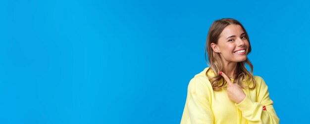 Closeup portrait of beautiful blond girl with short hair pointing at her piercing in ear smiling pro