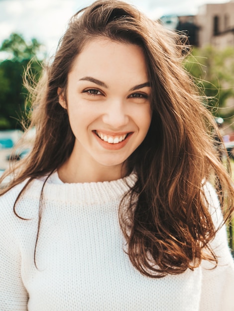 Closeup portrait of beautiful smiling brunette model. Trendy female posing in the street 