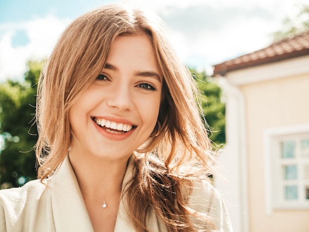 Closeup portrait of beautiful smiling brunette model. Trendy female posing in the street 