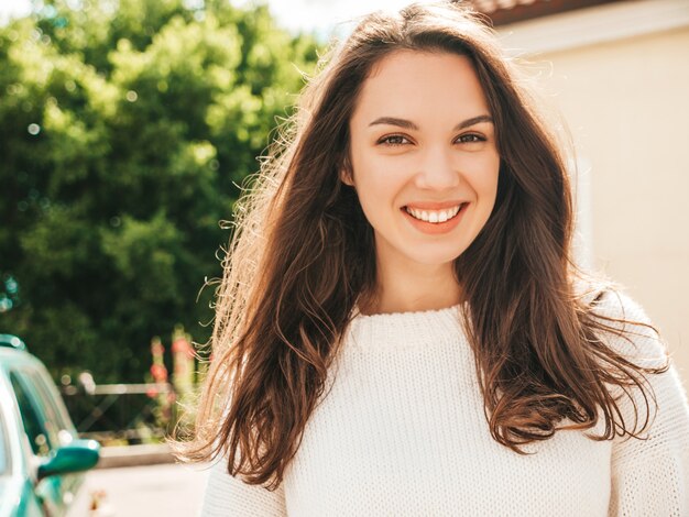 Closeup portrait of beautiful smiling brunette model. Trendy female posing in the street 