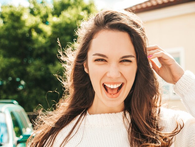 Closeup portrait of beautiful smiling brunette model. Trendy girl posing in the street 