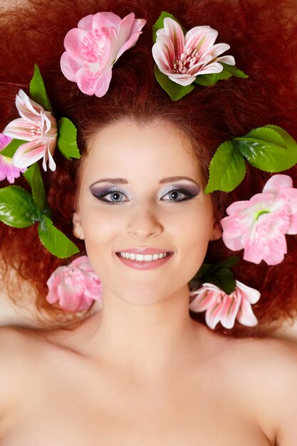 머리에 화려한 꽃과 아름다운 웃는 빨간 머리 생강 여자 얼굴의 근접 촬영 초상화