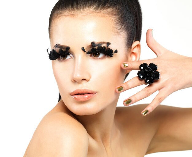 Closeup portrait of the beautiful woman with long black false eyelashes makeup and golden nails.  isolated on white background