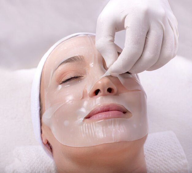 Closeup portrait of a beautiful young Caucasian female applying face skin mask