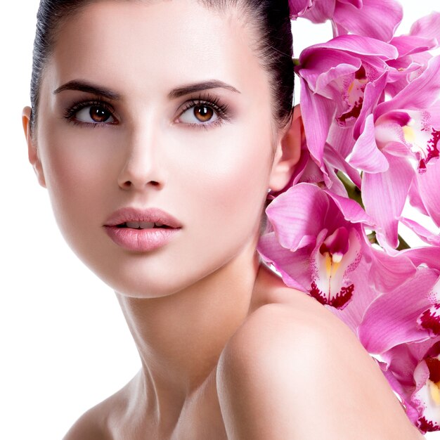 Closeup portrait of beautiful young pretty woman with healthy skin and flowers close to face - isolated on white.