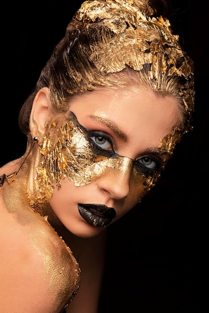 Closeup portrait of beautiful young woman with golden foil on face