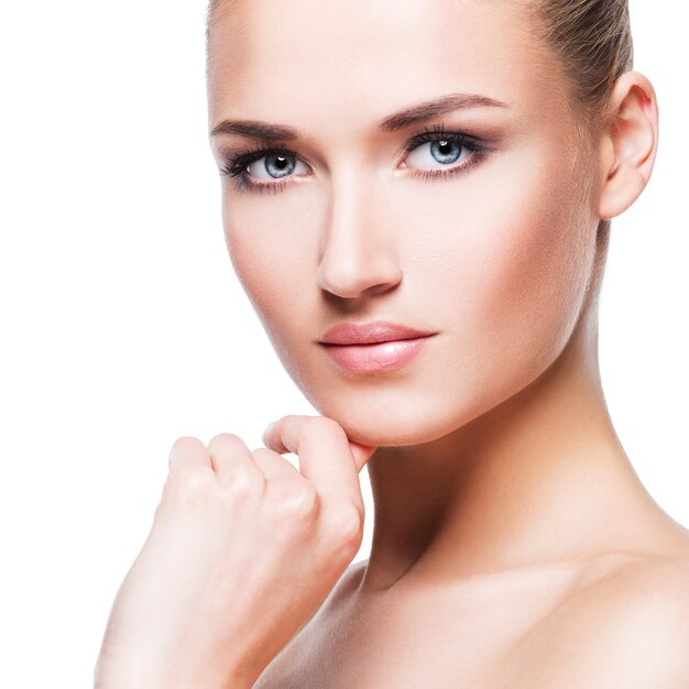 Closeup portrait of beautiful young woman with hand near face - isolated on white wall.