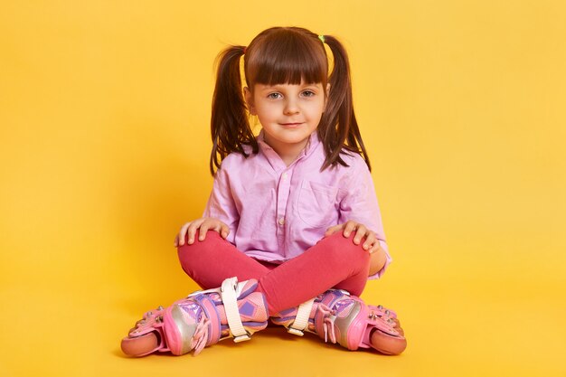 Closeup portrait of calm little girl sitting on floor with crossed legs