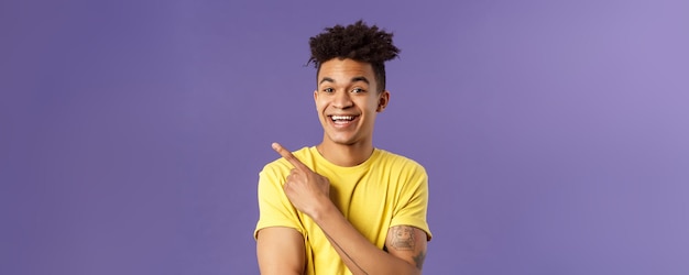 Free photo closeup portrait of cheerful attractive young male student showing promo pointing at upper left corn