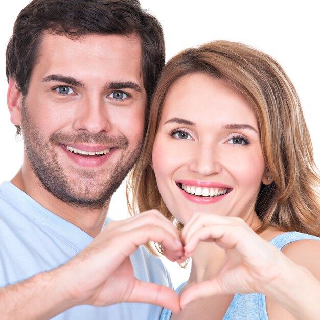 Closeup portrait of of cheerful smiling couple standing together show hands heart -  isolated