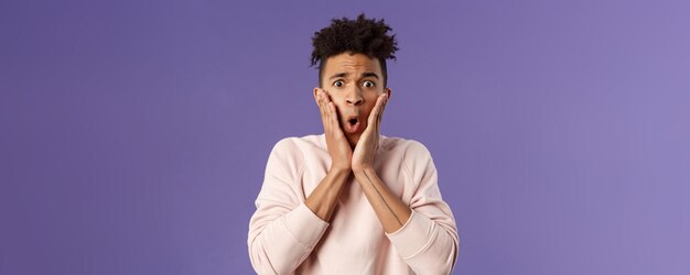 Closeup portrait of concerned embarrassed young man hold hands on cheeks looking desperate and alarm