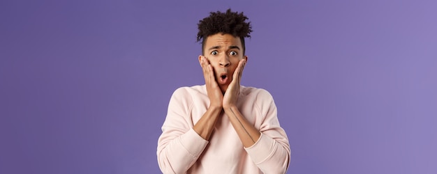 Closeup portrait of concerned embarrassed young man hold hands on cheeks looking desperate and alarm