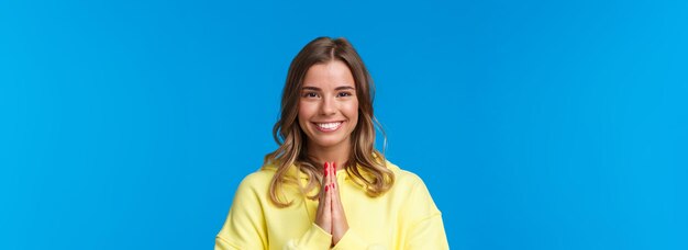 Ritratto del primo piano della ragazza bionda sorridente allegra sveglia con i capelli corti stringono le mani insieme in namaste