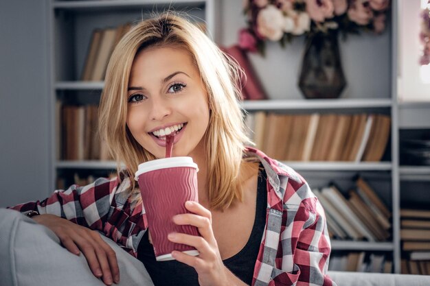 朝のコーヒーを飲むかわいい笑顔のブロンドの女性のクローズアップの肖像画。