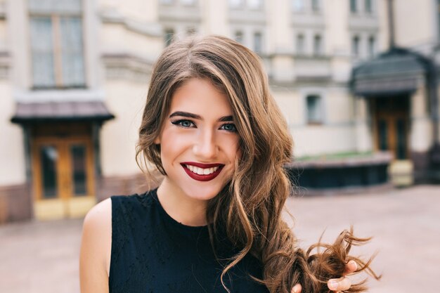 Closeup portrait of effective girl with long curly hair smiling