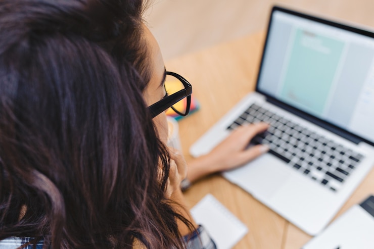 Free Photo closeup portrait from back brunette young woman in black glasses working with laptop on table. surfing in internet, clever student, freelancer, working, searching, designing.