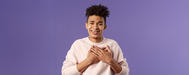 Closeup portrait of handsome silly hispanic guy with dreads place hands on heart and sighing as cont