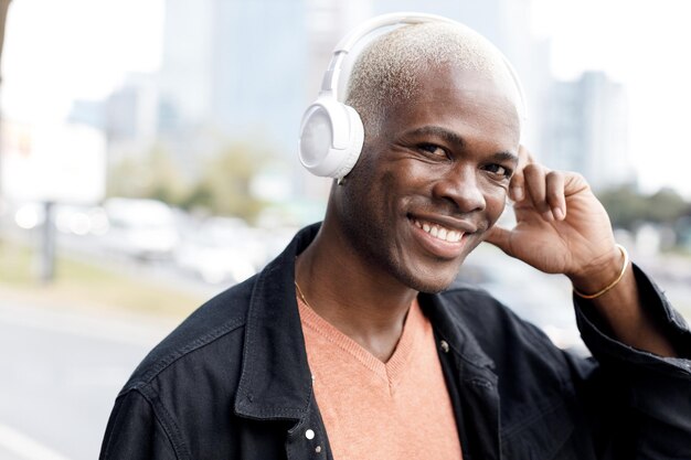 closeup portrait of a handsome smiling black man with headphones outdoors