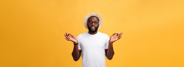 Closeup portrait of happy handsome young man in meditation yoga mode isolated on yellow background s