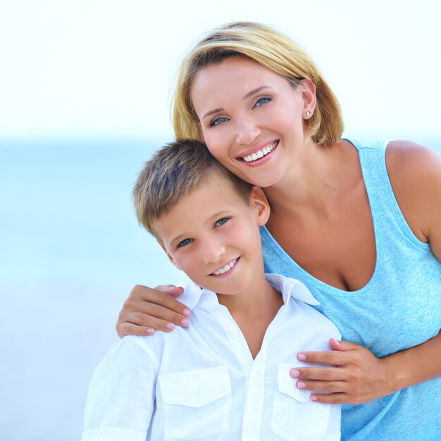 Closeup portrait of happy mother and son in embrace on the beach.
