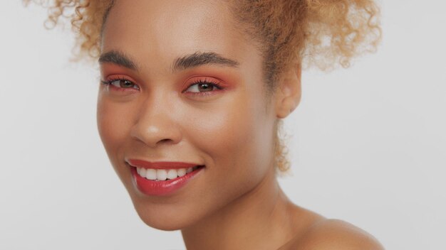 Closeup portrait of mixed rase woman with red makeup in studio close up smiling and watching to the camera