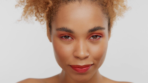 Free photo closeup portrait of mixed rase woman with red makeup in studio with head down watching to the camera