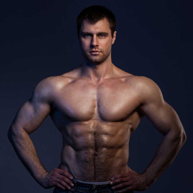 Closeup portrait of muscular guy in dark