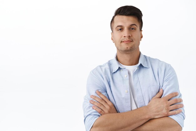 Closeup portrait of satisfied handsome adult masculine man cross arms on chest like professional pleased pose smiling camera promote gym or company service standing white background assured