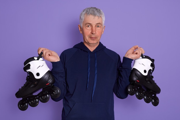 Closeup portrait of senior man being ready to roller skating outdoors.