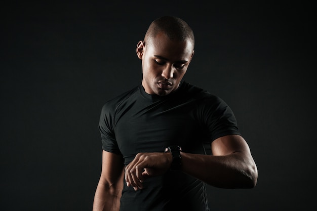 Closeup portrait of serious afro american sports man checking time on his hand