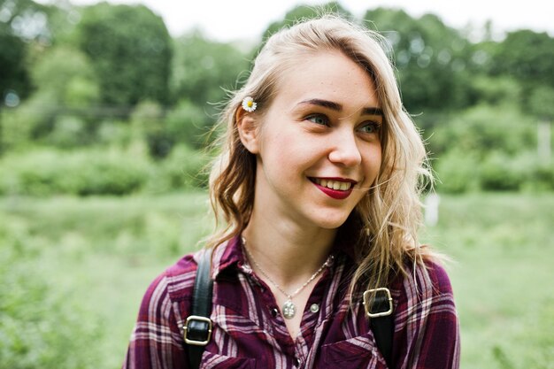 Closeup portrait of a smiling blond girl in tartan shirt in the countryside