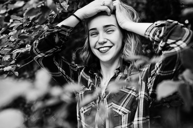 Closeup portrait of a smiling blond girl in tartan shirt in the countryside