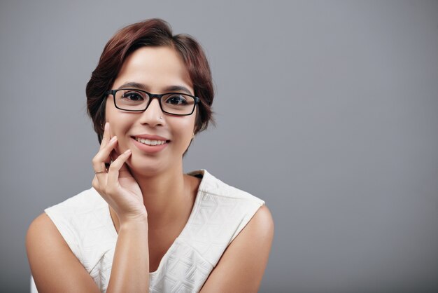 Closeup portrait of smiling Indian woman looking at camera against grey background