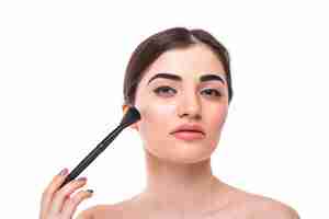 Free photo closeup portrait of a woman applying dry cosmetic tonal foundation on the face using makeup brush.