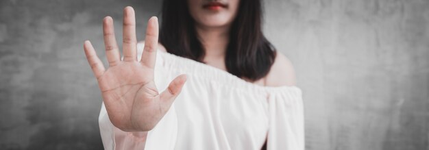 Closeup portrait young annoyed angry woman with bad attitude giving talk to hand gesture with palm outward isolated grey wall background. Negative human emotion face expression feeling body language.