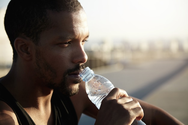 Closeup portrait of young bearded man drinking water