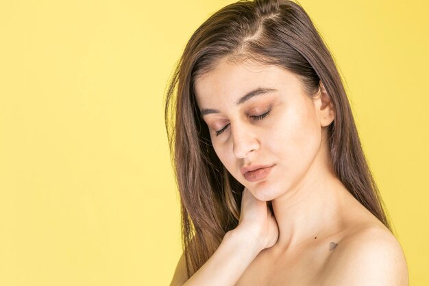 Closeup portrait of young beautiful girl holding her hand to her neck and closed her eyes