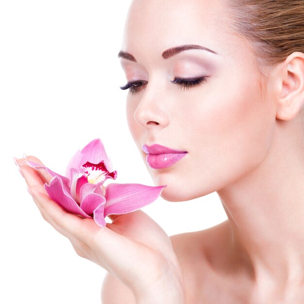 Closeup portrait of young beautiful  girl with flower near the face  - isolated on white wall